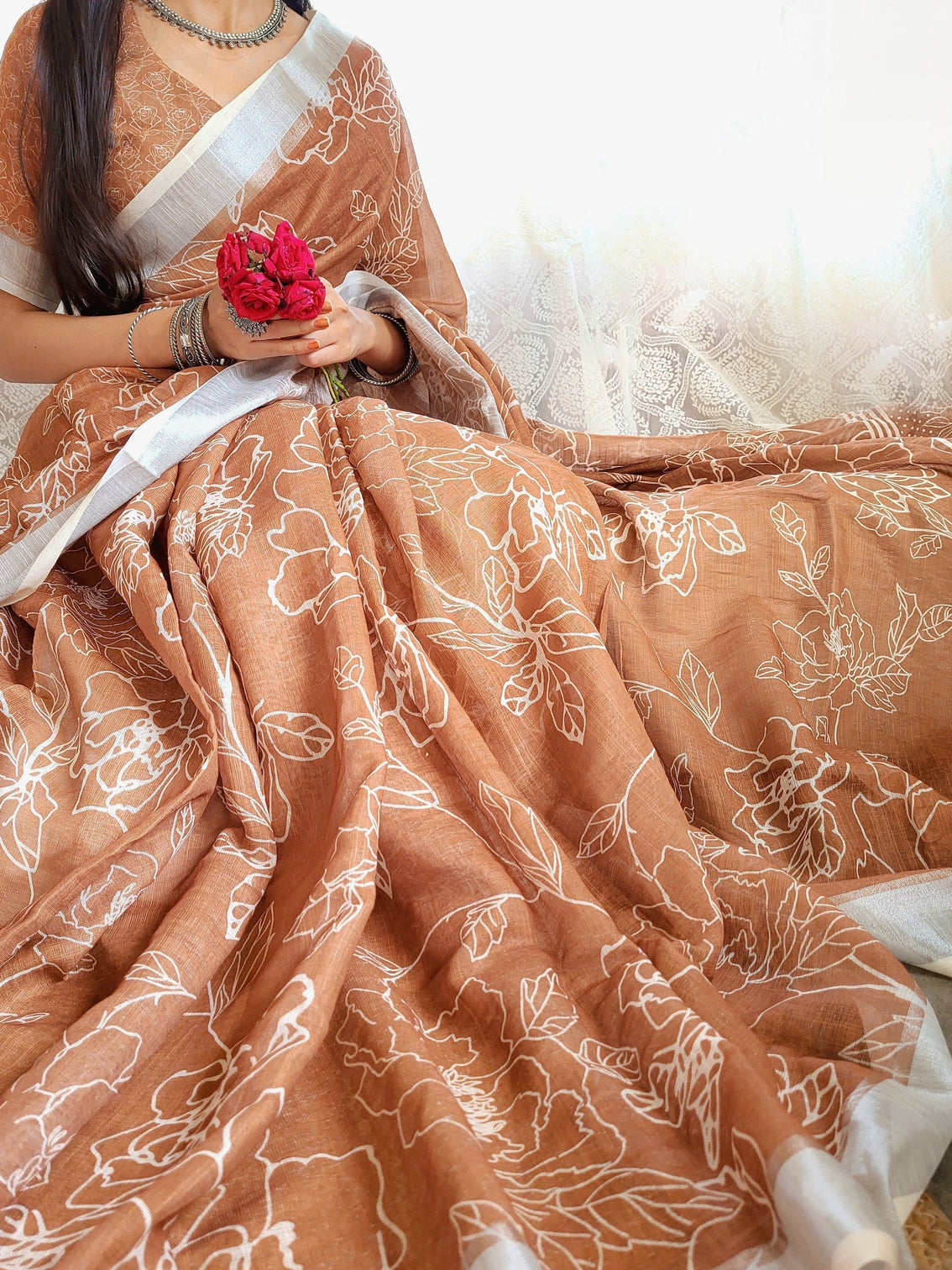 Rust brown pure linen saree with white floral motifs and tassel detailing